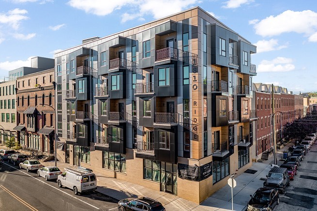 View of modern apartments among brownstone architecture. Photo via Instagram user @omegahomebuilders