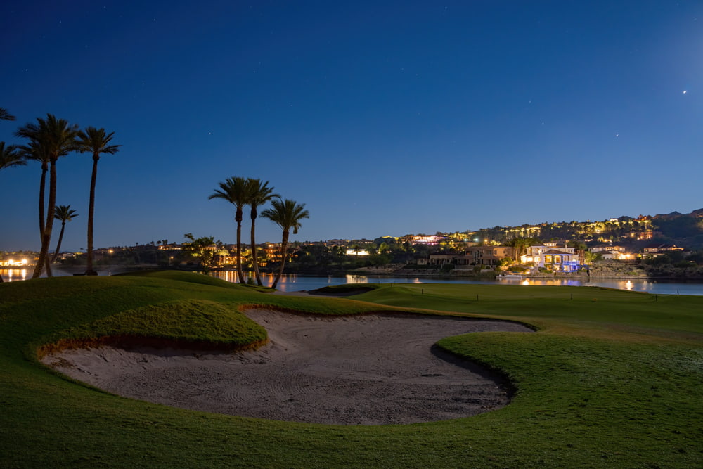 Las Vegas golf course in front of light-studded lake and hills at dusk