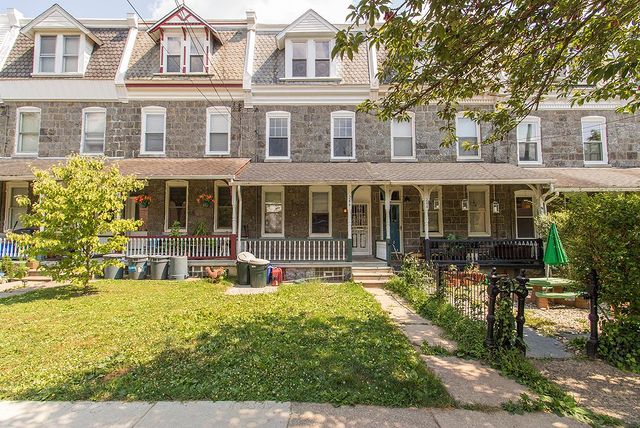 Brown row houses with a green lawn, sidewalk, and tree. Photo via Instagram user @crystaldrealtor