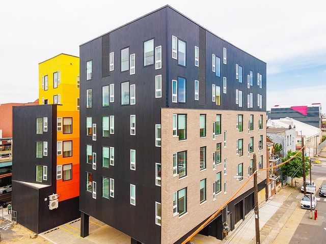 Corner view of a big, colorful, sleek, and modern apartment building. Photo via Instagram user @the_magnet_philly_