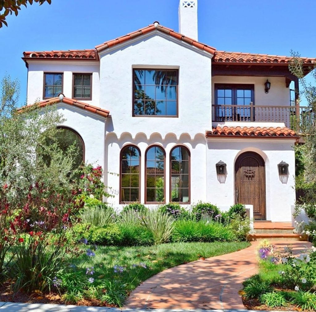 White two-story home with red Spanish-style roof and brick walkway leading to the door in Poway, California.