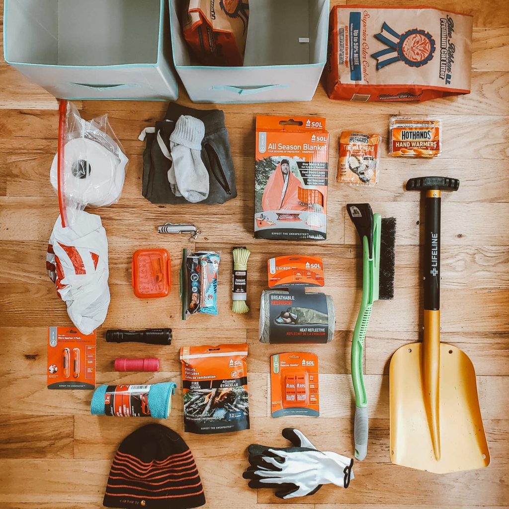 An overhead shot of emergency items on a wooden floor including a mini shovel, hat, gloves, rope, and more. Photo via Instagram user @mymountainwild