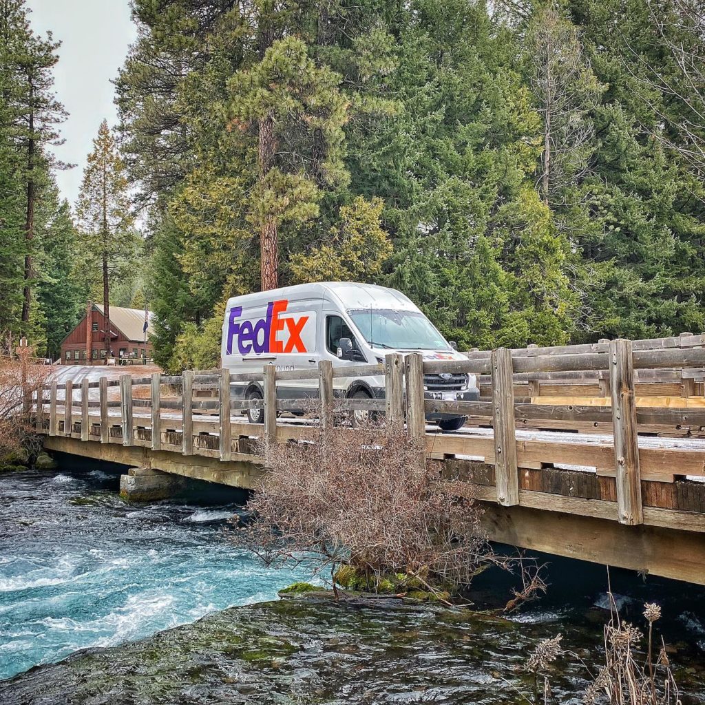 Fed Ex truck travelling over a wooden bridge and clear blue water in an alpine forest. Photo via Instagram user @pnw_explorer96