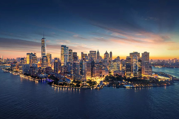 Sunset aerial view of lit up Manhattan Island surrounded by the East River