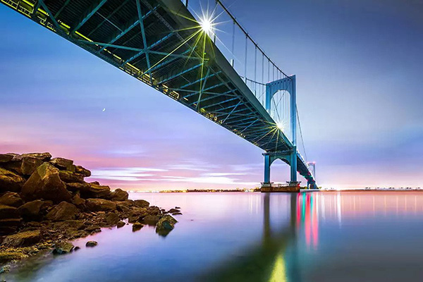 Whitestone Bridge with twinkling lights across the East River at sunset