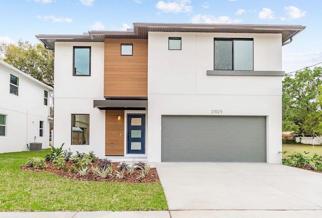 Modern white and wood-paneled home with light blue sky. Photo by Instagram user @domainhomesinc.