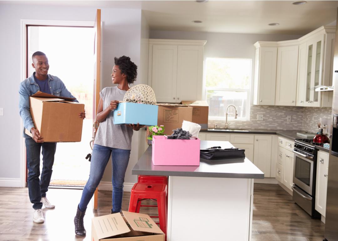 Young couple moving boxes into empty kitchen