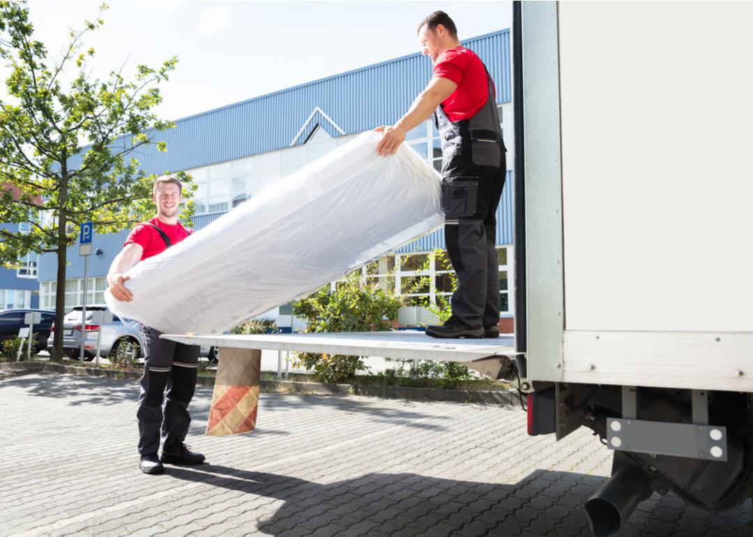 Two professional movers carrying furniture out of moving truck