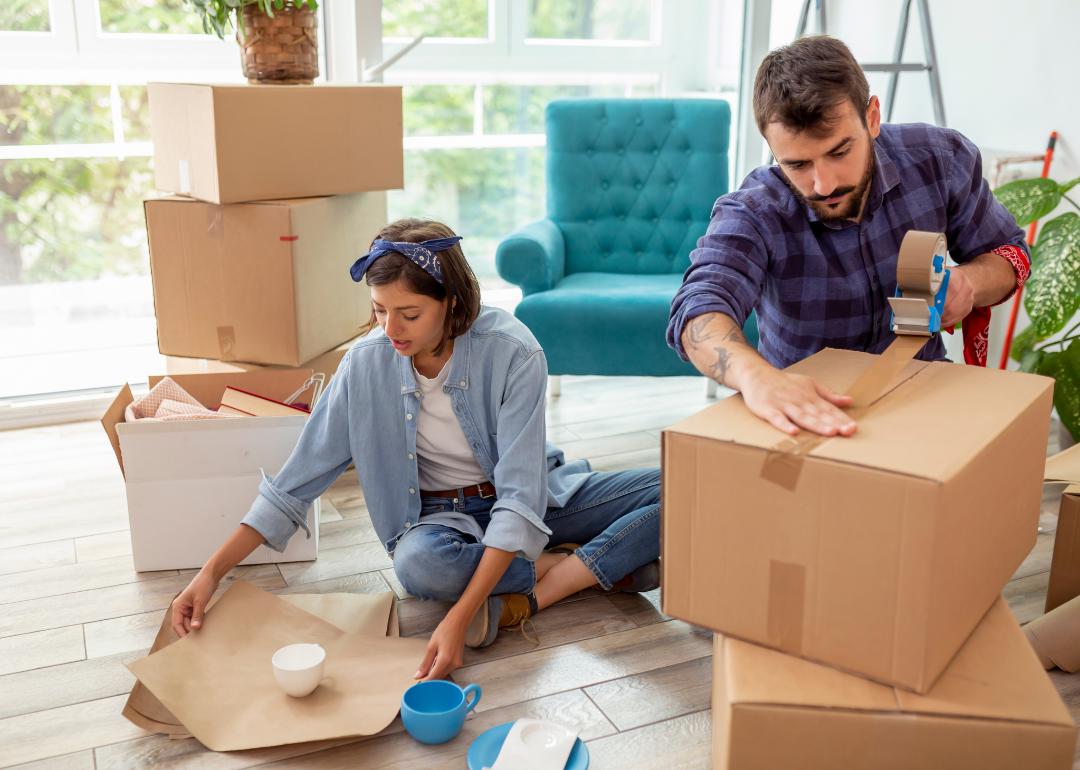Young couple packing moving boxes inside home