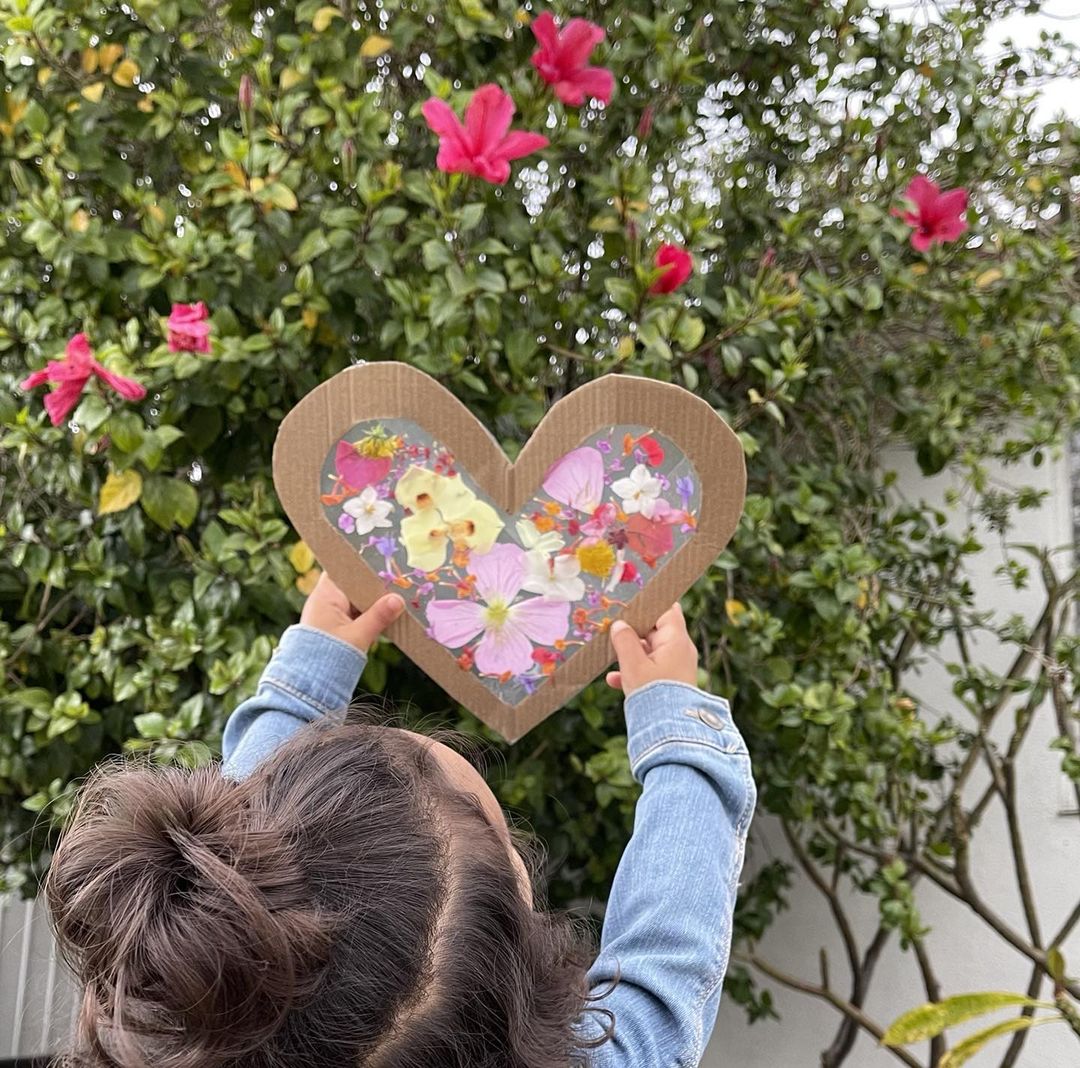 Child holding up heart shaped craft with flowers. Photo by Instagram user @chelle_kelemen