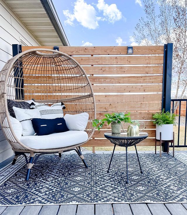 A backyard wooden privacy screen with a patio chair and plants. Photo by Instagram user @themontanamodern