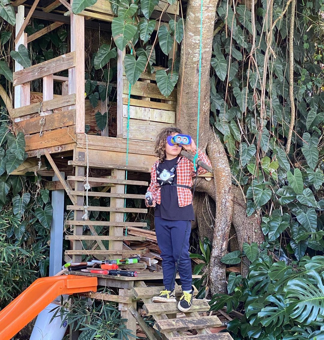 Kid using binoculars outside a backyard treehouse. Photo by Instagram user @pamrika.