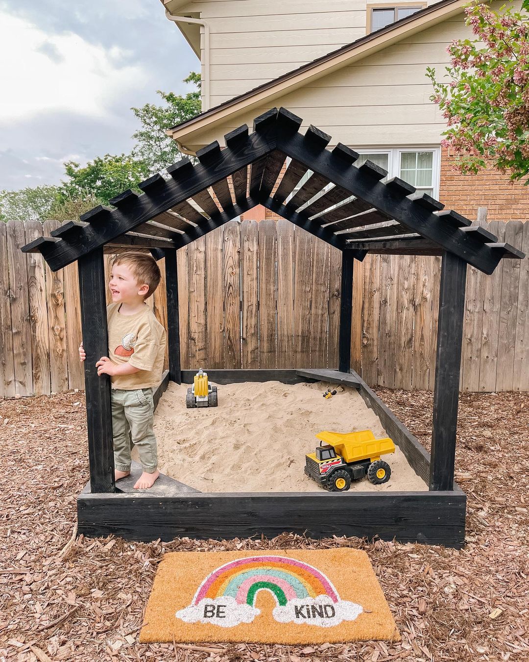 Wooden sandbox with sand toys and play mat. Photo by Instagram user @life.with.kaylee.blog