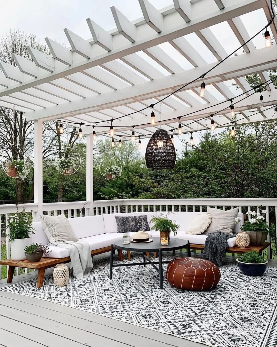 bright daytime outdoor space with white wooden pergola and black string lights. Photo by Instagram user @jmexsuss_us