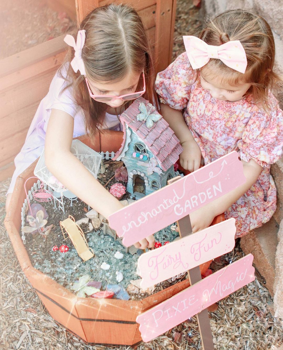 Children designing a fairy garden with small trinkets and pink accents. Photo by Instagram user @heidiliz