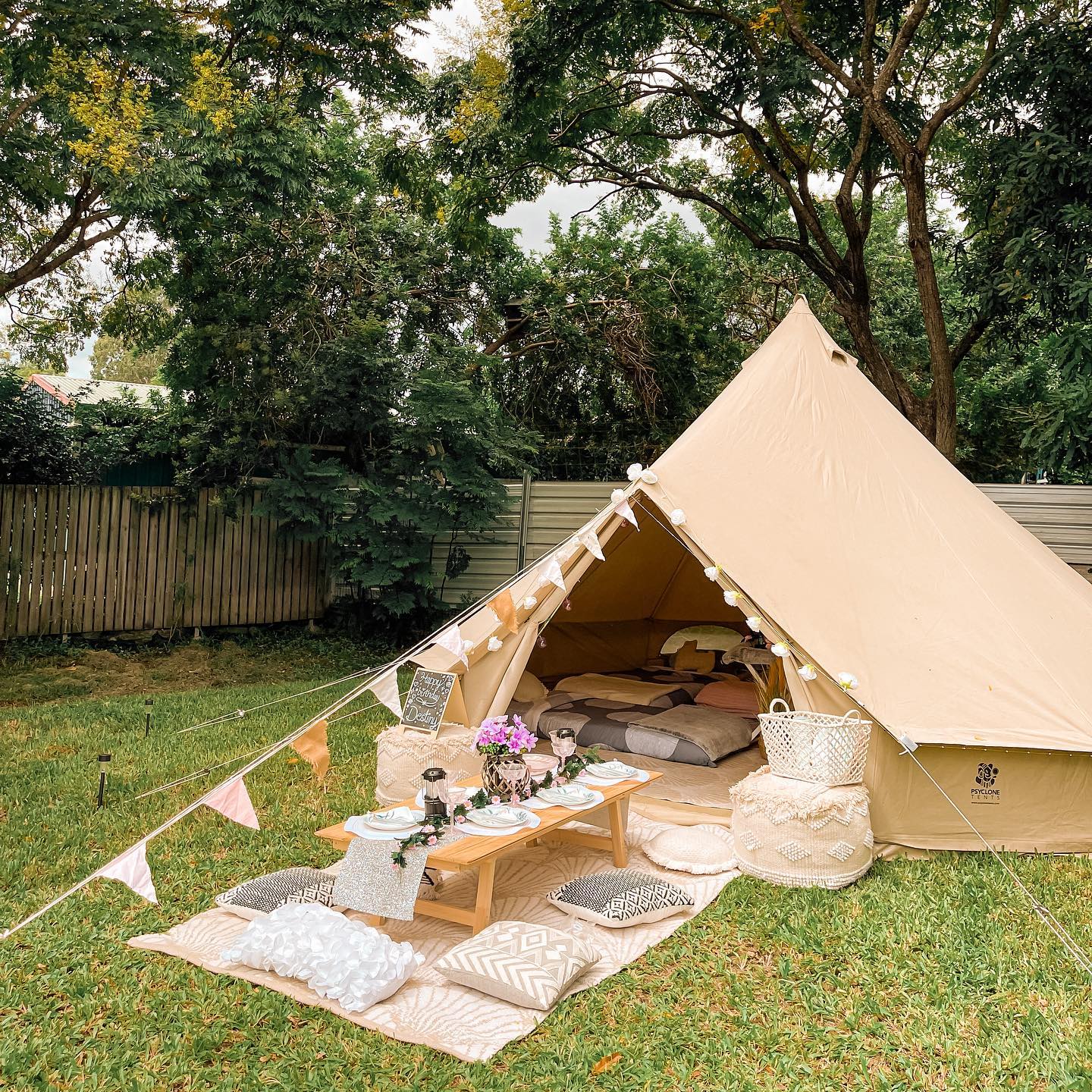 Backyard tent with blankets, floor cushions, and small table. Photo by Instagram user @glamparoo