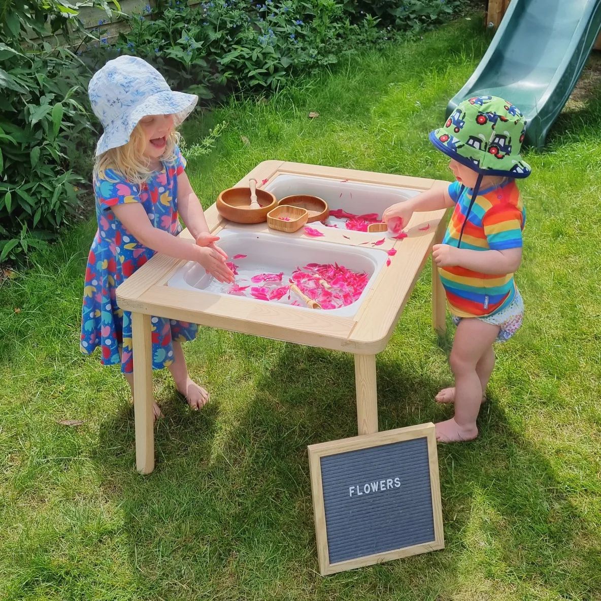 Children playing with flowers in an outdoor water table. Photo by Instagram user @the_future_is_yours_11