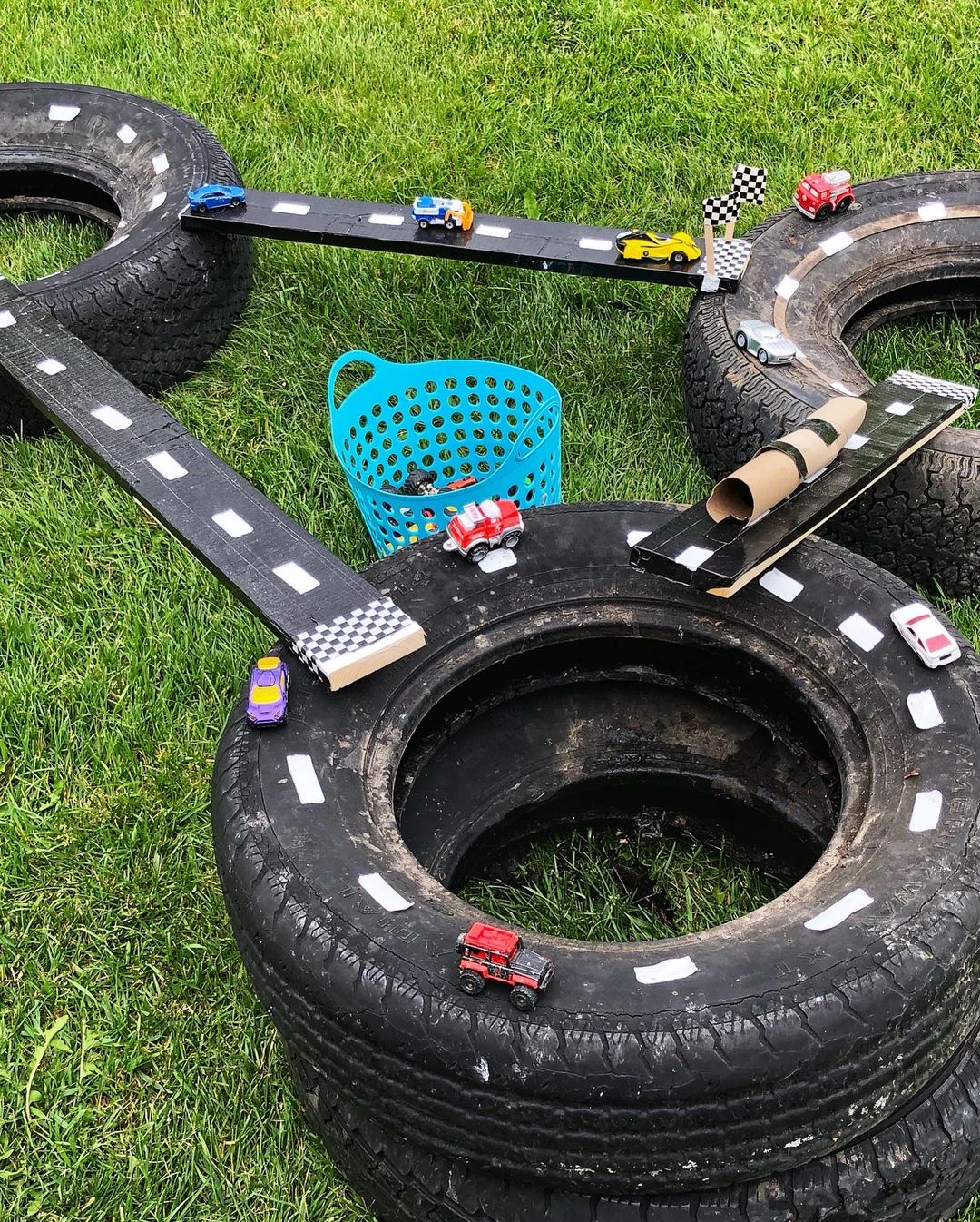 DIY racetrack with old tires, wood planks, and toy cars. Photo by Instagram user @goldendaysdayhome