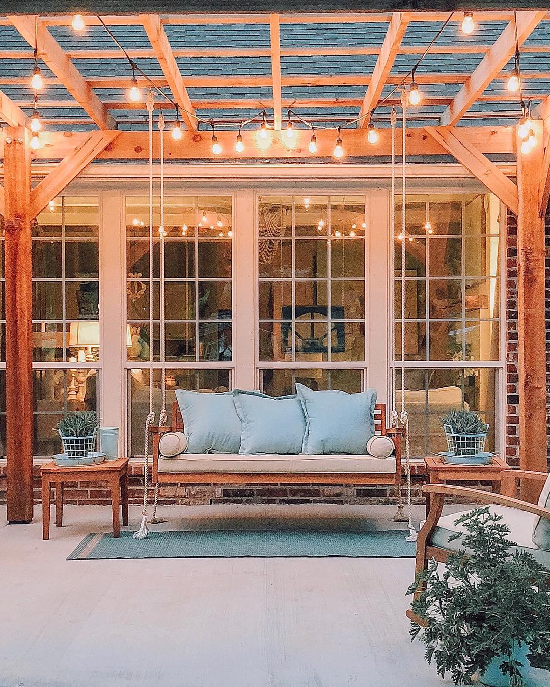 Backyard outdoor space with pergola that is lit with string lights. Photo by Instagram user @cottonstem.