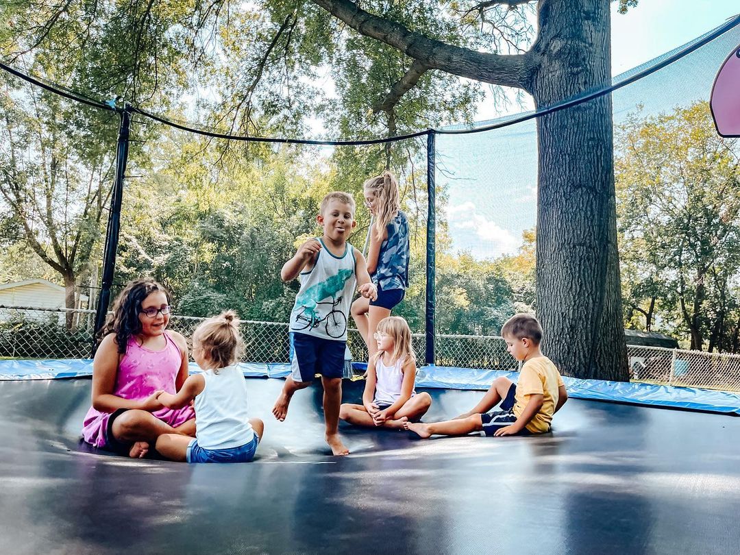 Family jumping on a large backyard trampoline. Photo by Instagram user @coffeebooksandyoga
