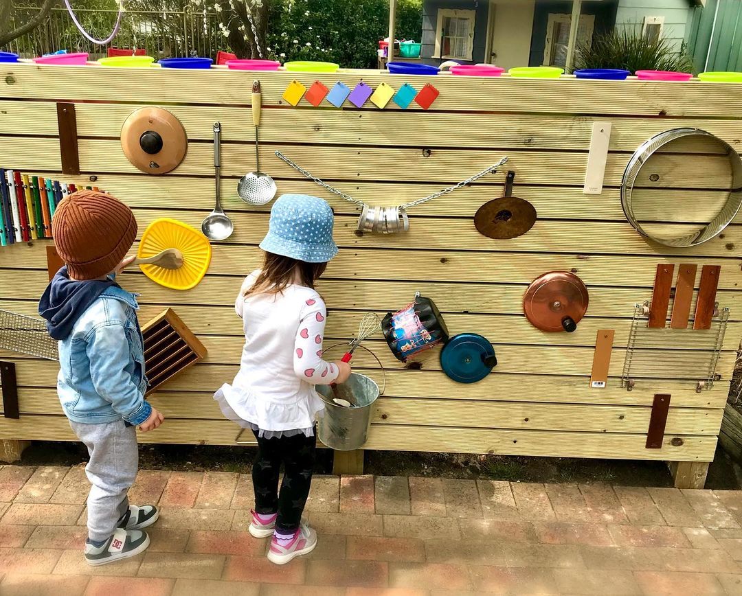 Wooden sound wall with pots, pans, and other items. Photo by Instagram user @brookes_family_day_care