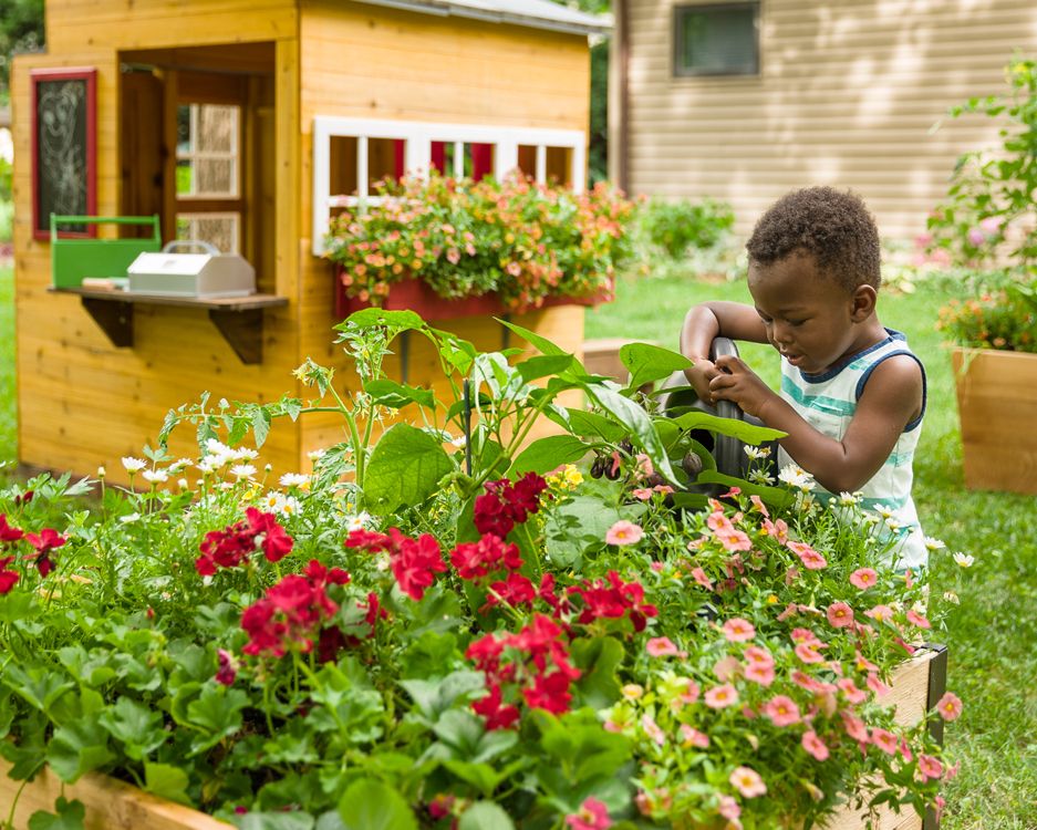 Child watering a flower bed. Photo by Instagram user @provenwinners