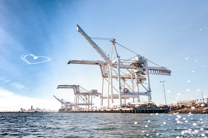 Port of Oakland during the day with a heart shape cloud on the top left corner of the sky. Photo by Instagram username @portoakland