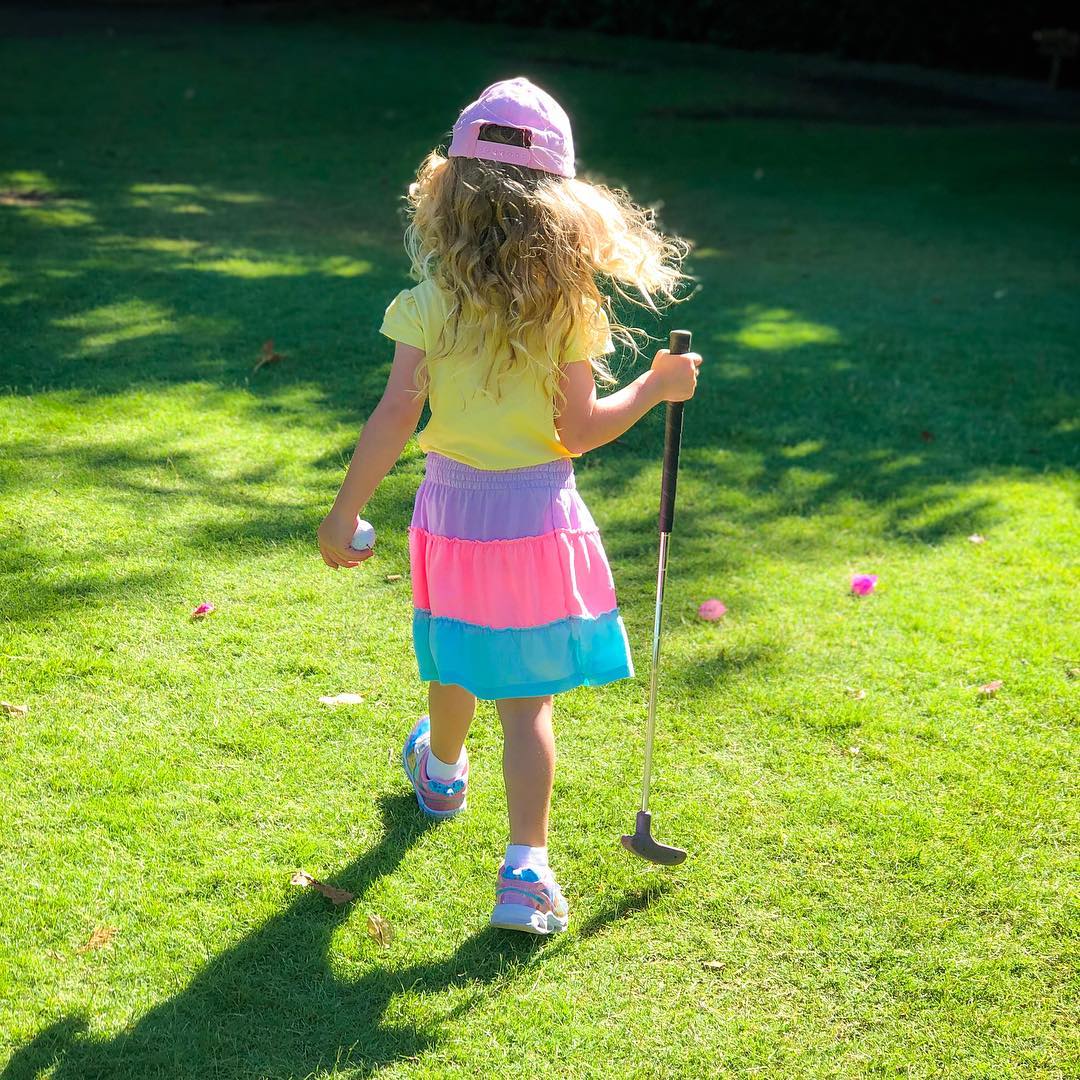 Child holding putter and golf ball. Photo by Instagram user @nadia_e_westbrook_creative
