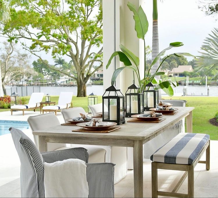 Coastal style backyard space with enclosed lanterns on a dining room table. Photo by Instagram user @lovecoastaliving