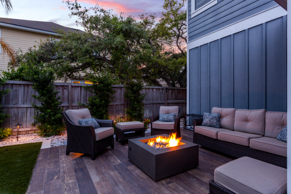 A backyard with patio furniture and a fire pit at dusk