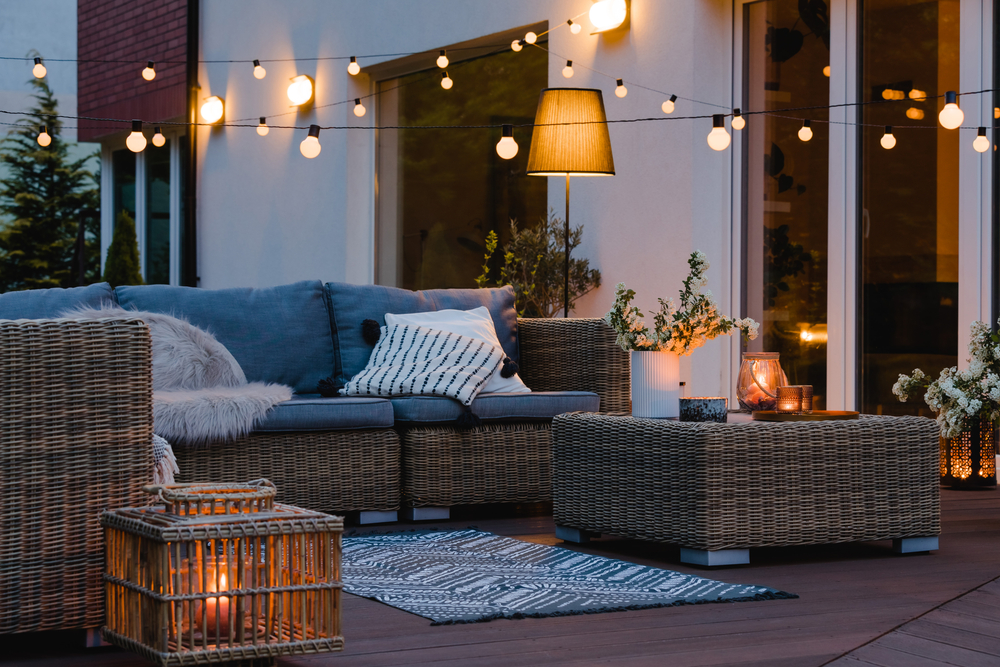 A backyard patio with furniture and lights at dusk