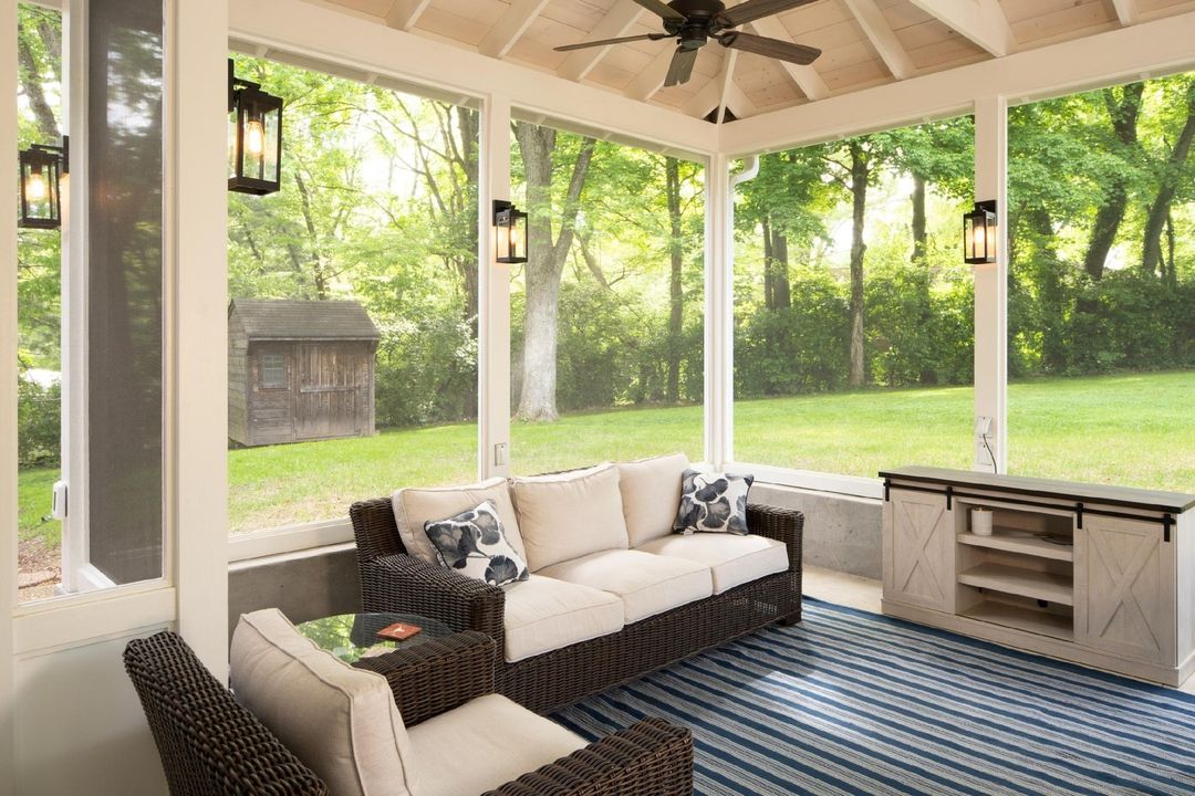 A screened in enclosed patio with lanterns and a ceiling fan. Photo by Instagram user @ecolivinghomejax