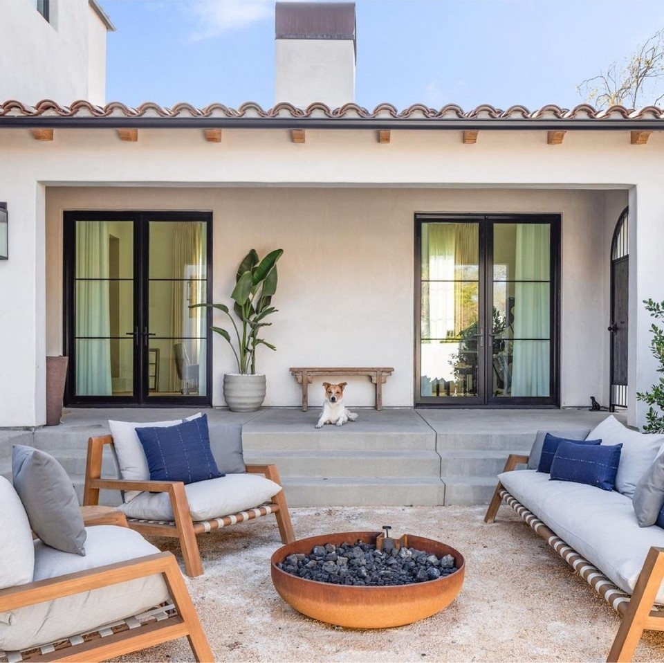 A lowered backyard patio space with stairs leading up to the home. Photo by Instagram user @houzz