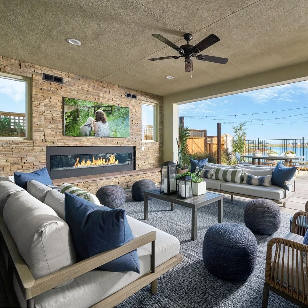 A covered backyard patio with a mounted TV and fireplace. Photo by Instagram user @newhomesource