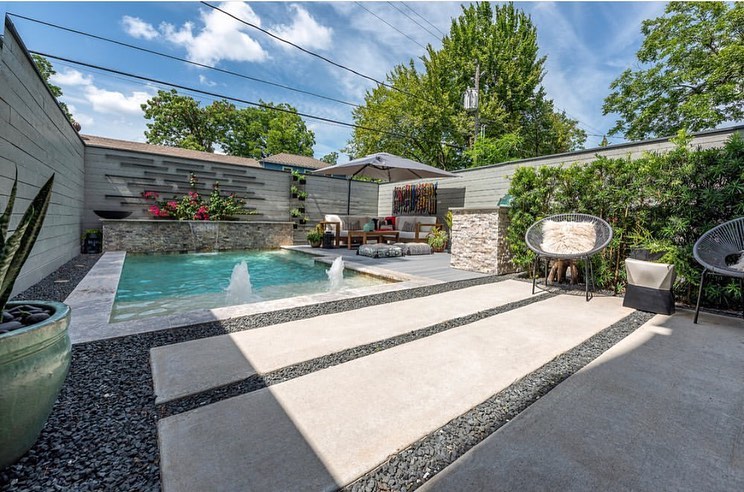 A backyard patio with water feature and a patio furniture set under an umbrella. Photo by Instagram user @the_aesthetic_side_of_homes