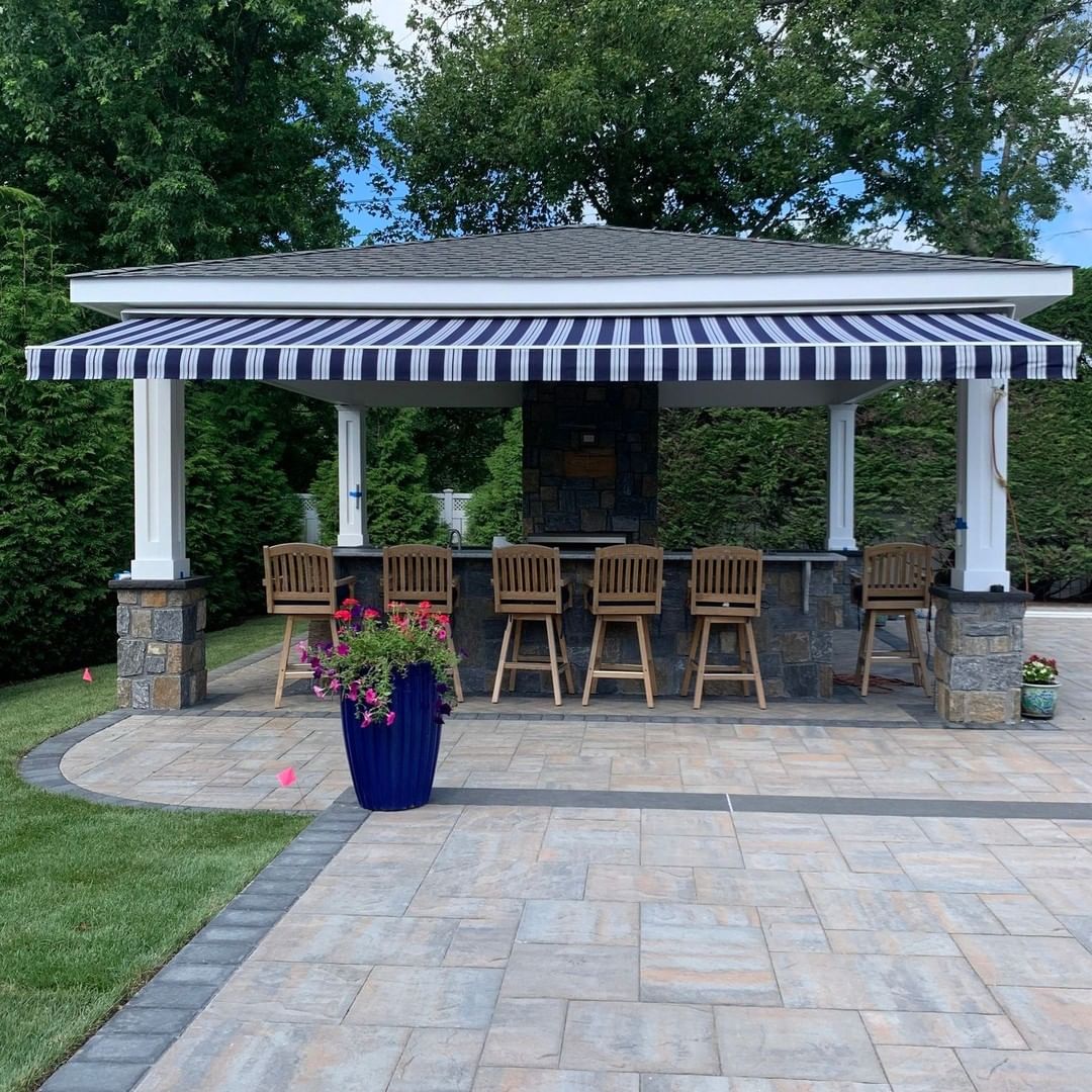 Outdoor dining set beneath a striped retractable awning. Photo by Instagram user @mmawning.