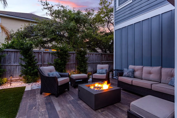 A lit fire pit surrounded by outdoor furniture at sunset
