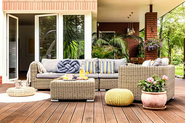 Wicker outdoor furniture set surrounded by plants on a wooden deck