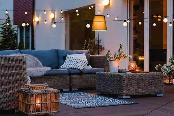 rattan wicker sofa patio set with ottoman sitting under string lights outside