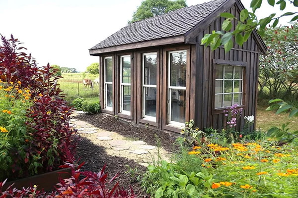 Backyard greenhouse shed with a stone path and garden