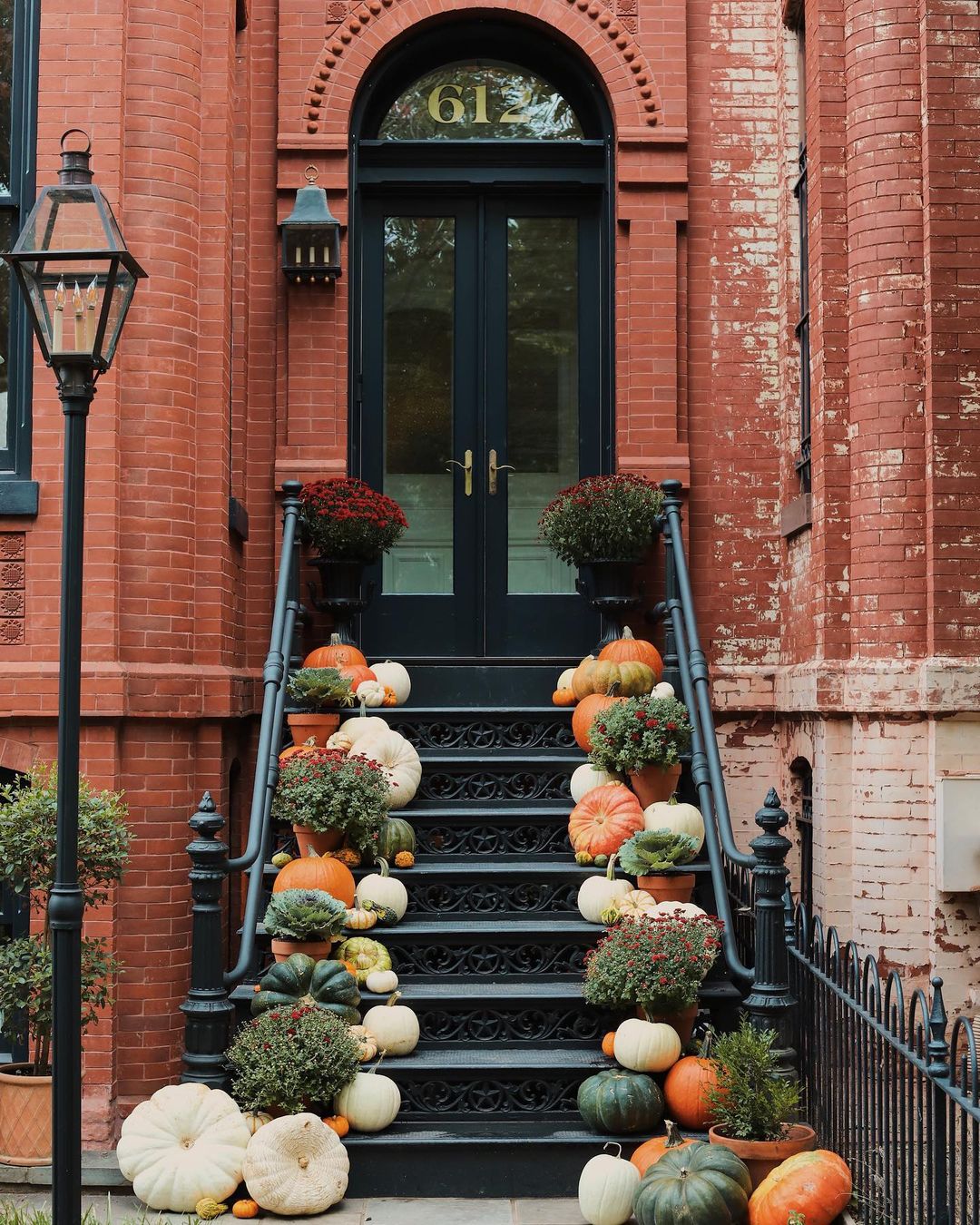 The exterior of a brick townhome with a set of stairs leading to the front door, with pumpkins placed on each step. Photo by Instagram user @jyoungdesignhouse.