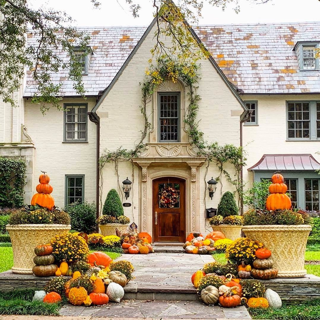 A Tudor-style home with pumpkins and other gourds arranged ornamentally around the porch and entryway. Photo by Instagram user @dollydallas1. 