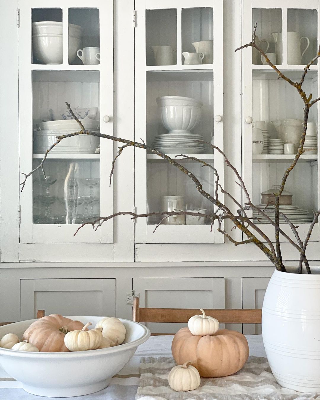 Pumpkins placed in a bowl and on the counter of a neutral kitchen. Photo by Instagram user @thegatheredloft.