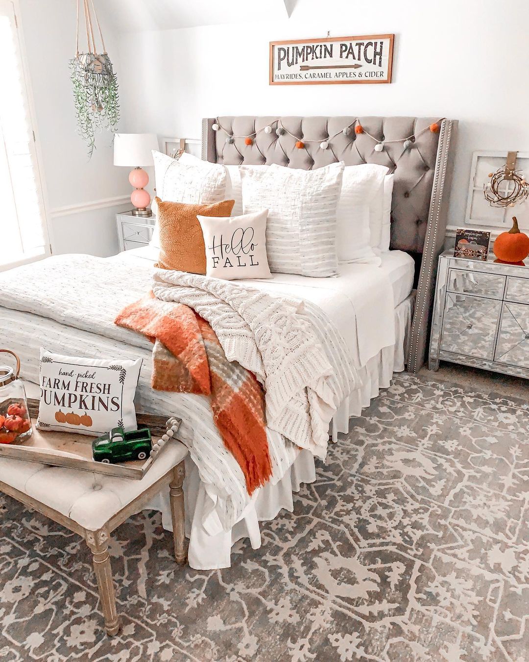 A guest bedroom with fall throw pillows and blankets on the bed and other fall decor throughout the space. Photo by Instagram user @rachelpuccetti.