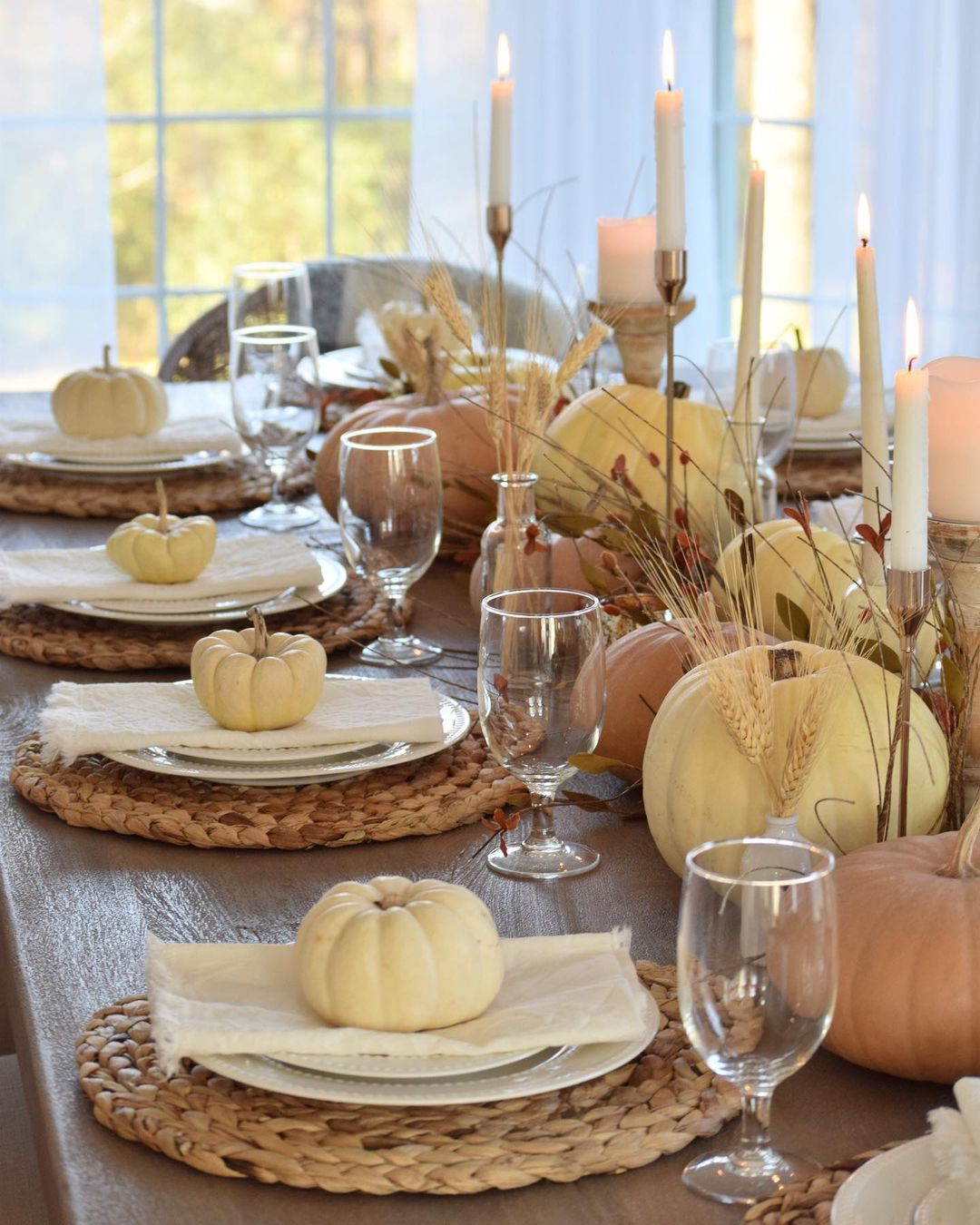 Pumpkins placed on plates at a table with fall produce as the centerpiece. Photo by Instagram user @onassisandclaire.