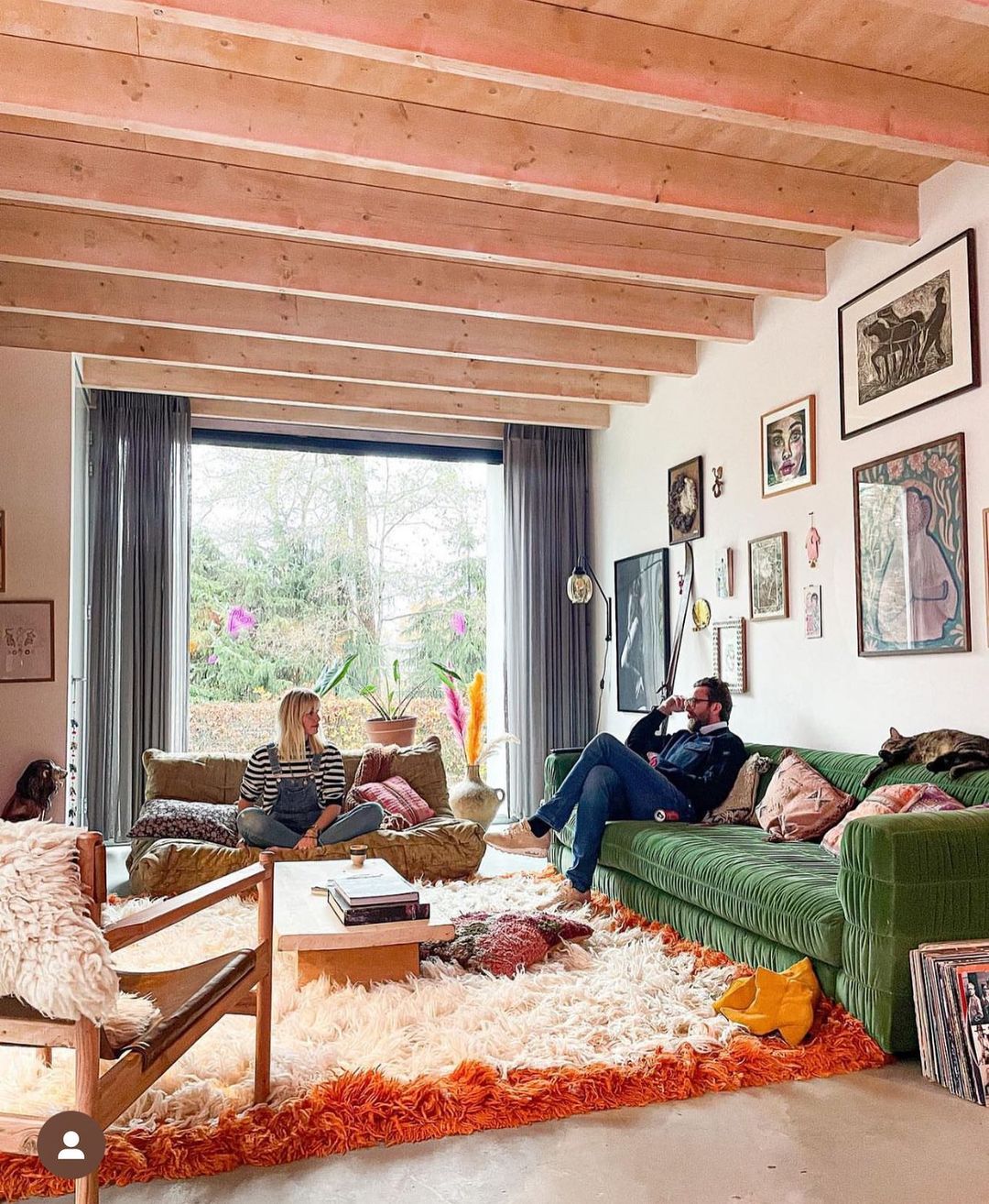 two people chatting in an open living room with green couch and orange rug. Photo by Instagram user @houseoforange