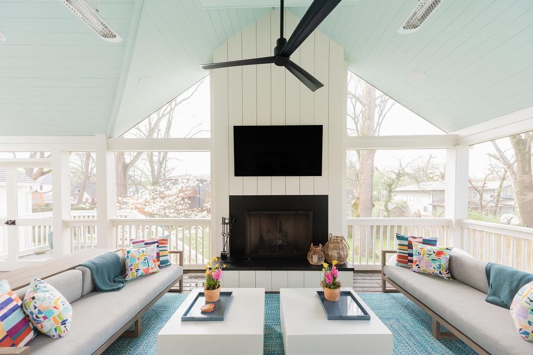 Screened porch area with seating, fireplace, and TV. Photo by Instagram user @merrillconstruction