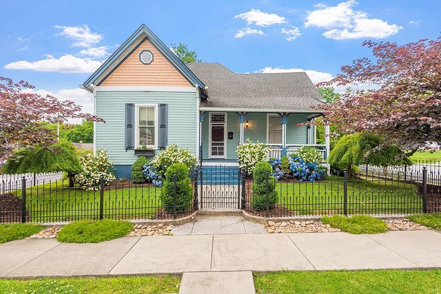 A green, well-trimmed, fenced yard in front of a seafoam Victorian home in Fourth & Gill. Photo by Instagram user @_vintagekelly_.