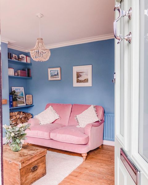 A light blue room with a pink couch up against the wall.