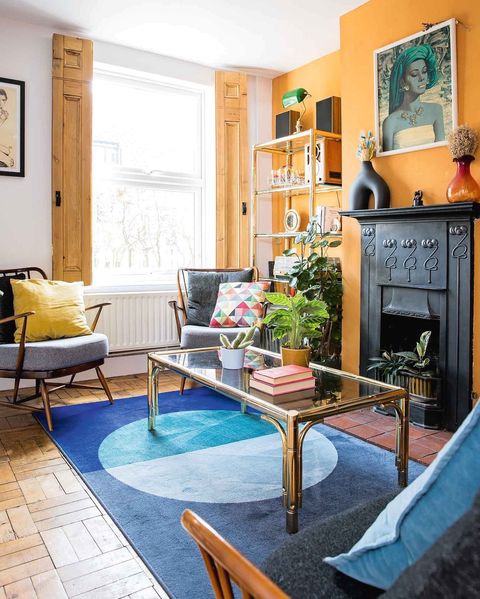 A room with orange walls with a blue rug in the middle of the room.